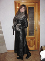 Stunning young woman in ankle length fur trimmed black leather coat